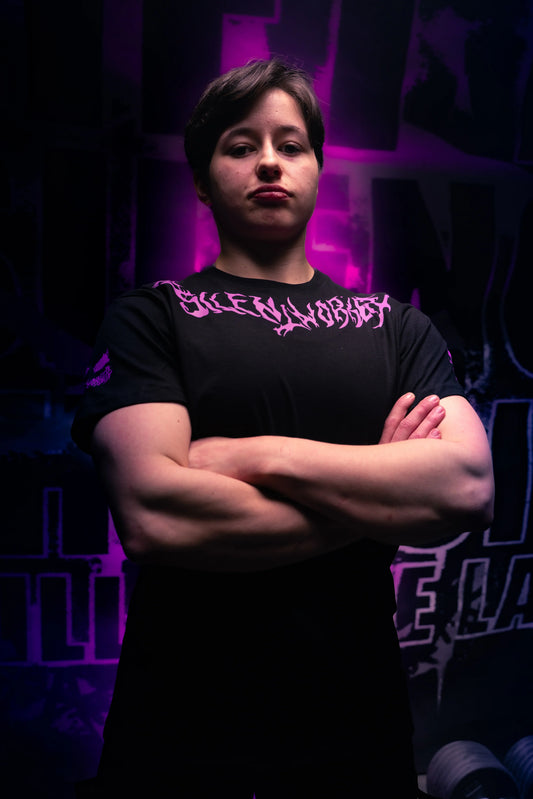 Powerlifter in Silent Worker apparel with arms crossed, gym background, purple lighting