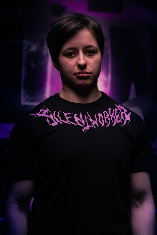 Person wearing Silent Worker powerlifting apparel with bold pink logo, purple-lit background