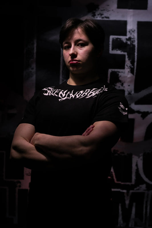 Powerlifter wearing Silent Worker Hong Kong black t-shirt with crossed arms against dark backdrop