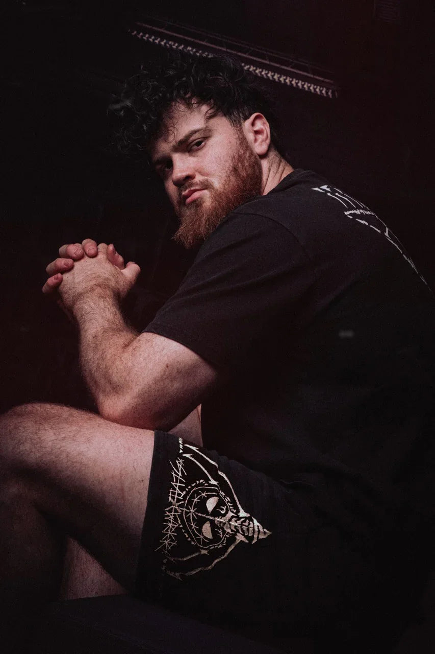 Man with beard wearing Silent Worker powerlifting apparel in dark gym setting