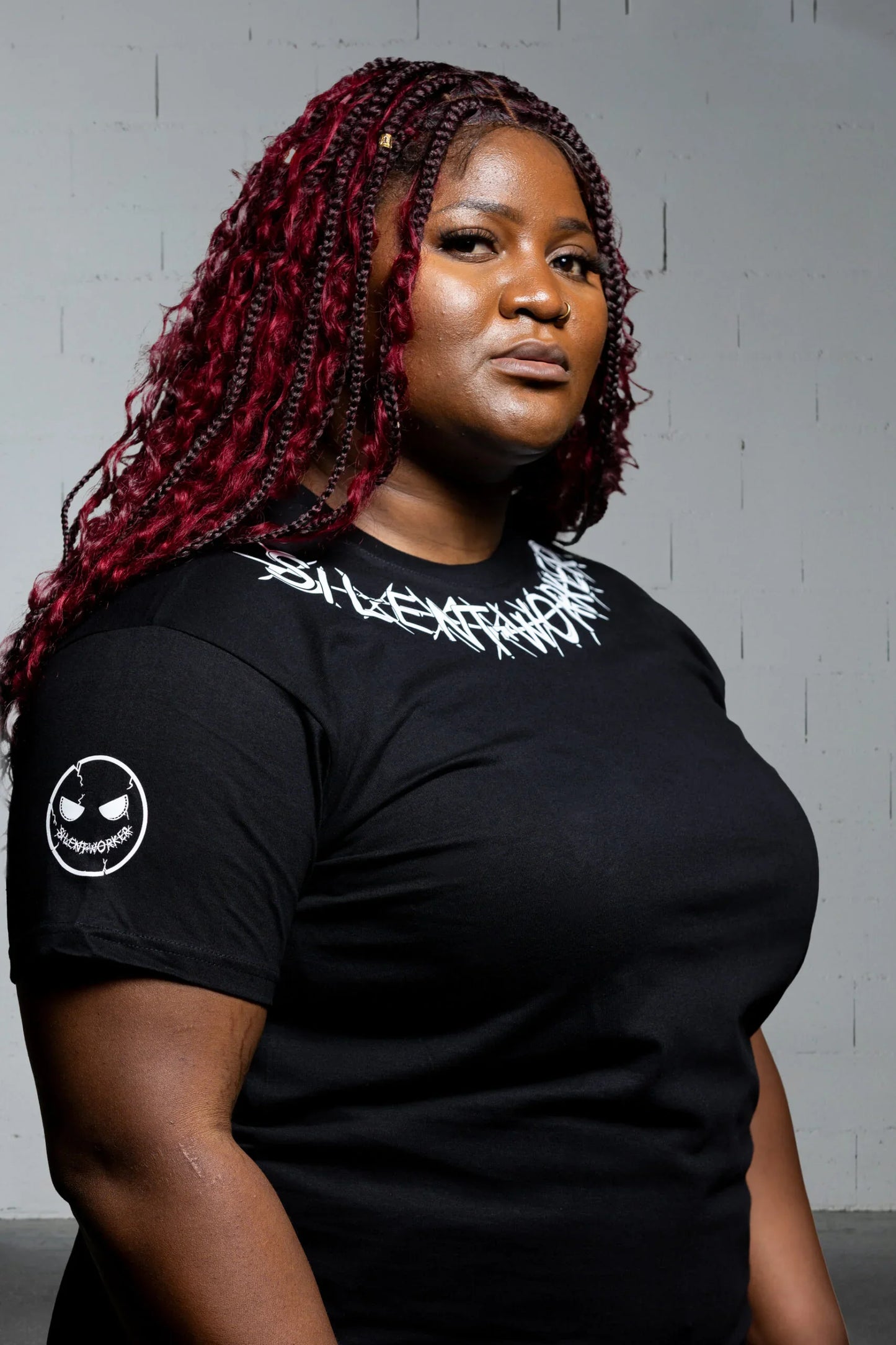 Woman wearing black Silent Worker powerlifting t-shirt with logo, studio background