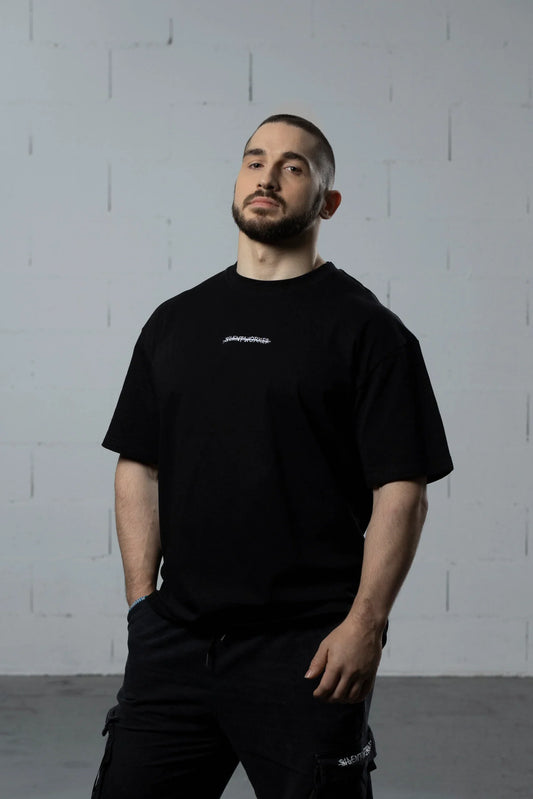 Man wearing Silent Worker black powerlifting t-shirt in minimalist studio setting